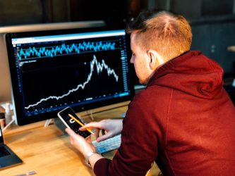 A man looking at a computer screen displaying a graph.